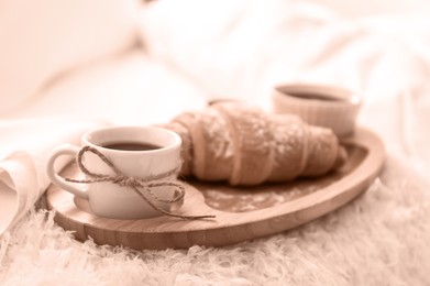 Image of Delicious morning coffee and croissant on bed, toned in mocha mousse shade. Trendy color of 2025 year