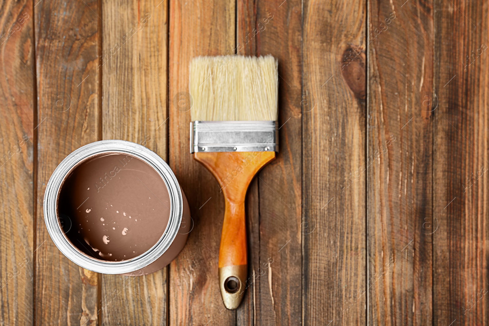 Image of Mocha mousse shade paint in can and brush on wooden background, top view. Trendy color of 2025 year