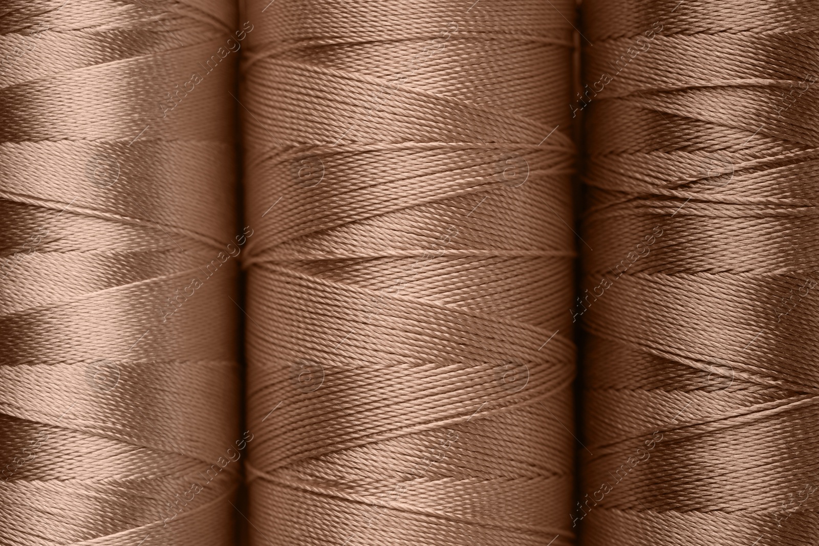 Image of Sewing threads in mocha mousse shades, closeup. Trendy color of 2025 year