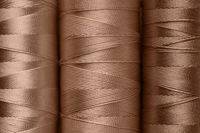 Image of Sewing threads in mocha mousse shades, closeup. Trendy color of 2025 year