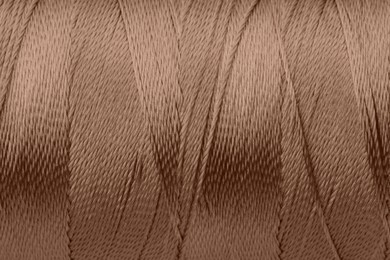 Image of Sewing thread in mocha mousse shade, closeup. Trendy color of 2025 year