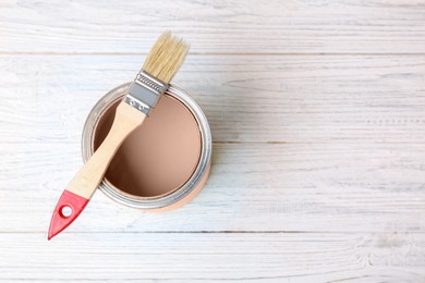 Image of Mocha mousse shade paint in can and brush on white wooden background, top view. Trendy color of 2025 year