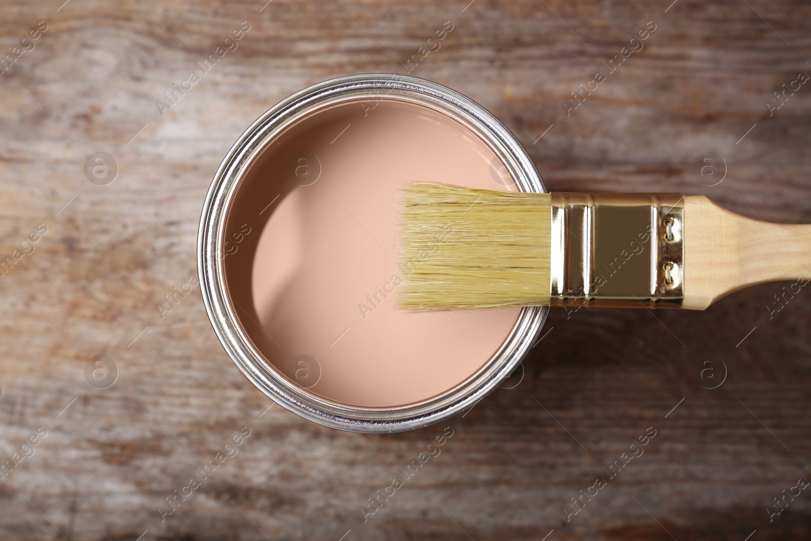 Image of Mocha mousse shade paint in can and brush on wooden background, top view. Trendy color of 2025 year