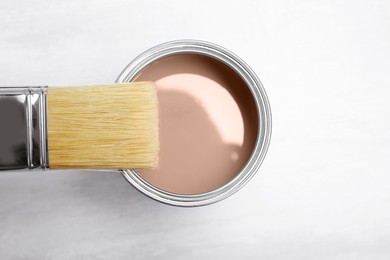 Image of Mocha mousse shade paint in can and brush on white background, top view. Trendy color of 2025 year