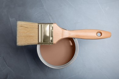 Image of Mocha mousse shade paint in can and brush on grey background, top view. Trendy color of 2025 year