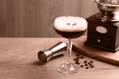 Image of Delicious espresso martini, coffee beans, manual grinder and jigger on wooden table, toned in mocha mousse shade. Trendy color of 2025 year