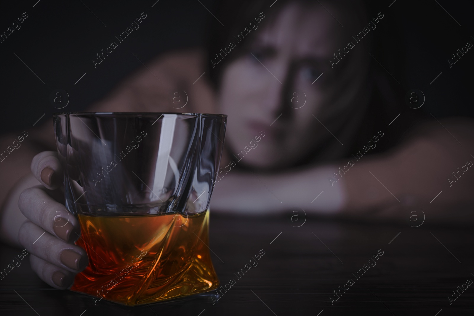 Image of Alcohol addiction. Depressed woman with whiskey at table, selective focus