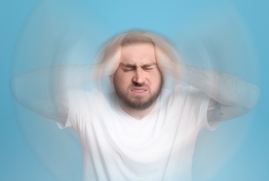 Image of Man suffering from headache and dizziness on light blue background