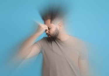 Image of Man suffering from headache and dizziness on light blue background