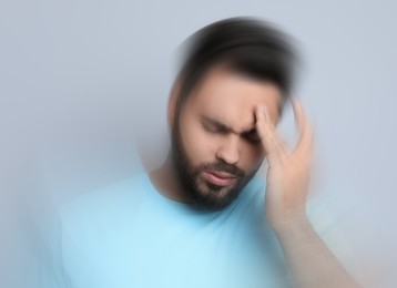 Image of Man suffering from headache and dizziness on grey background