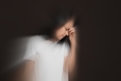 Image of Woman suffering from headache and dizziness on dark brown background