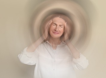 Woman suffering from headache and dizziness on dark beige background