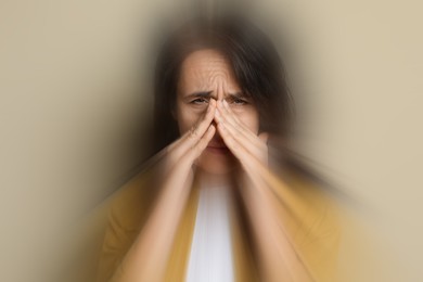 Image of Woman suffering from headache and dizziness on dark beige background