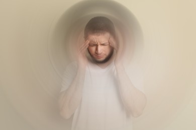 Image of Man suffering from headache and dizziness on dark beige background