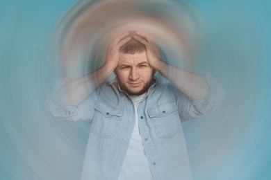 Image of Man suffering from headache and dizziness on light blue background