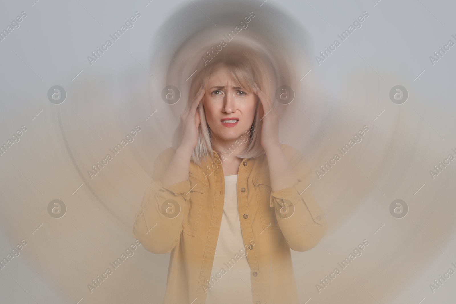 Image of Woman suffering from headache and dizziness on grey background