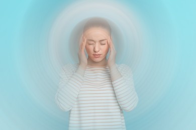 Image of Woman suffering from headache and dizziness on light blue background