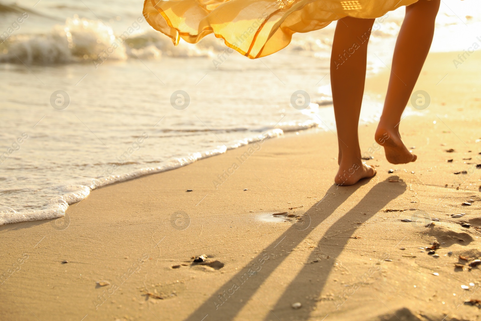 Photo of Young  woman walking on beach at sunset, closeup