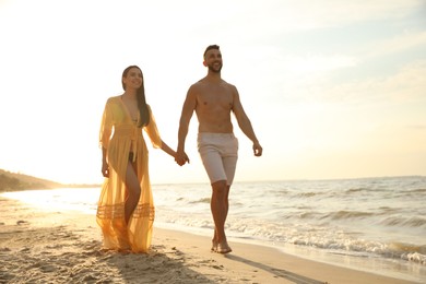 Photo of Happy young couple walking together on beach at sunset