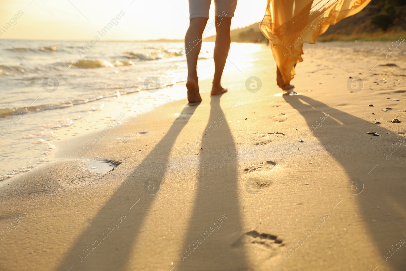 Photo of Couple walking together on beach at sunset, closeup