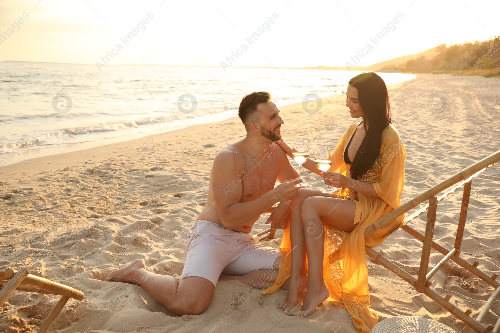 Photo of Romantic couple drinking wine together on beach at sunset