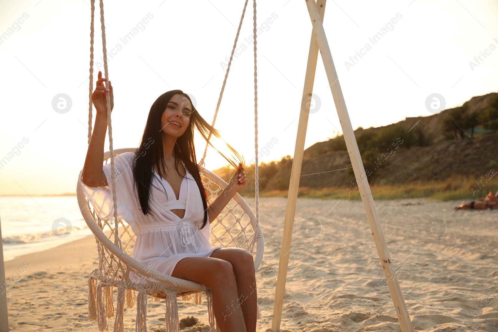 Photo of Young beautiful woman on swing chair at sunset