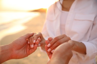 Photo of Lovely couple holding hands on beach at sunset, closeup