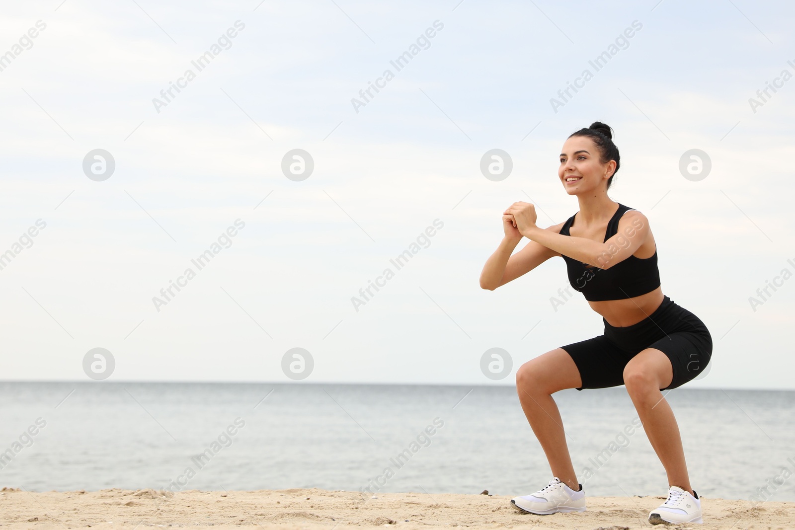 Photo of Young woman doing exercise on beach, space for text. Body training