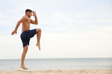 Photo of Muscular man doing exercise on beach, space for text. Body training