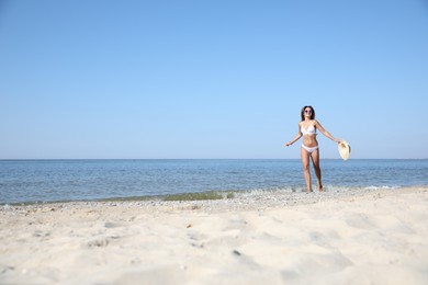 Photo of Young woman with beautiful body on sandy beach. Space for text