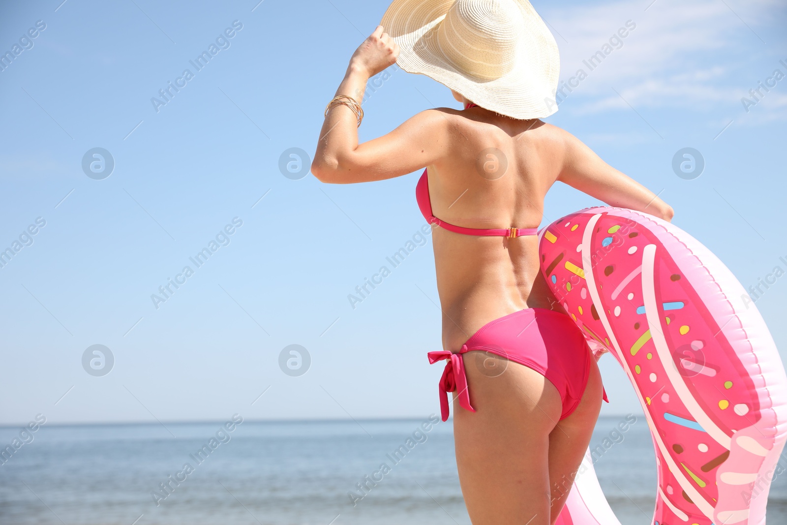 Photo of Young woman with beautiful body holding inflatable ring on beach. Space for text