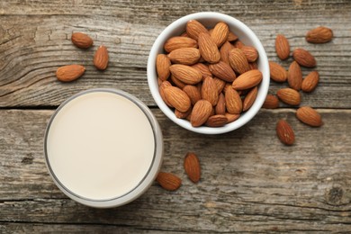 Photo of Fresh almond milk in glass and nuts on wooden table, top view