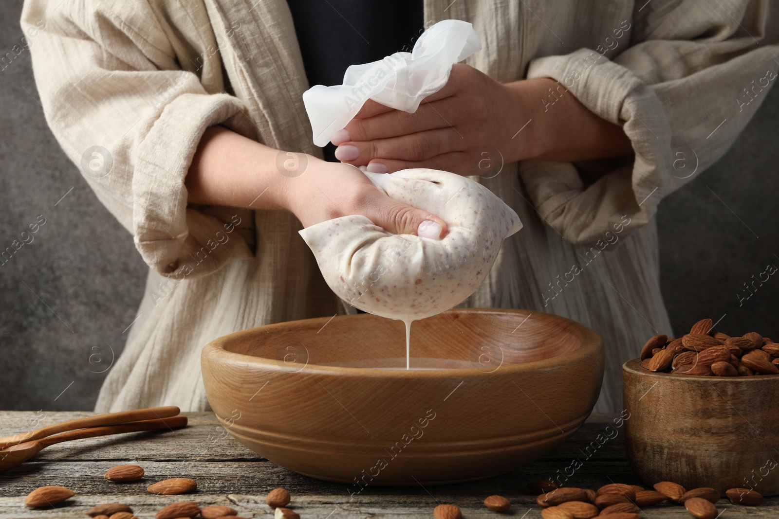 Photo of Woman making almond milk at wooden table, closeup