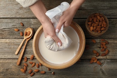 Photo of Woman making almond milk at wooden table, top view