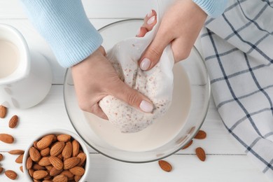 Photo of Woman making almond milk at white wooden table, top view