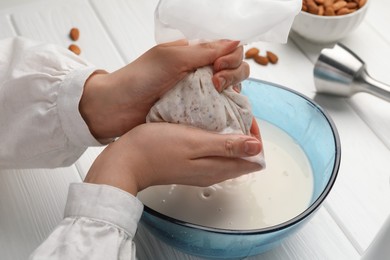 Photo of Woman making almond milk at white wooden table, closeup