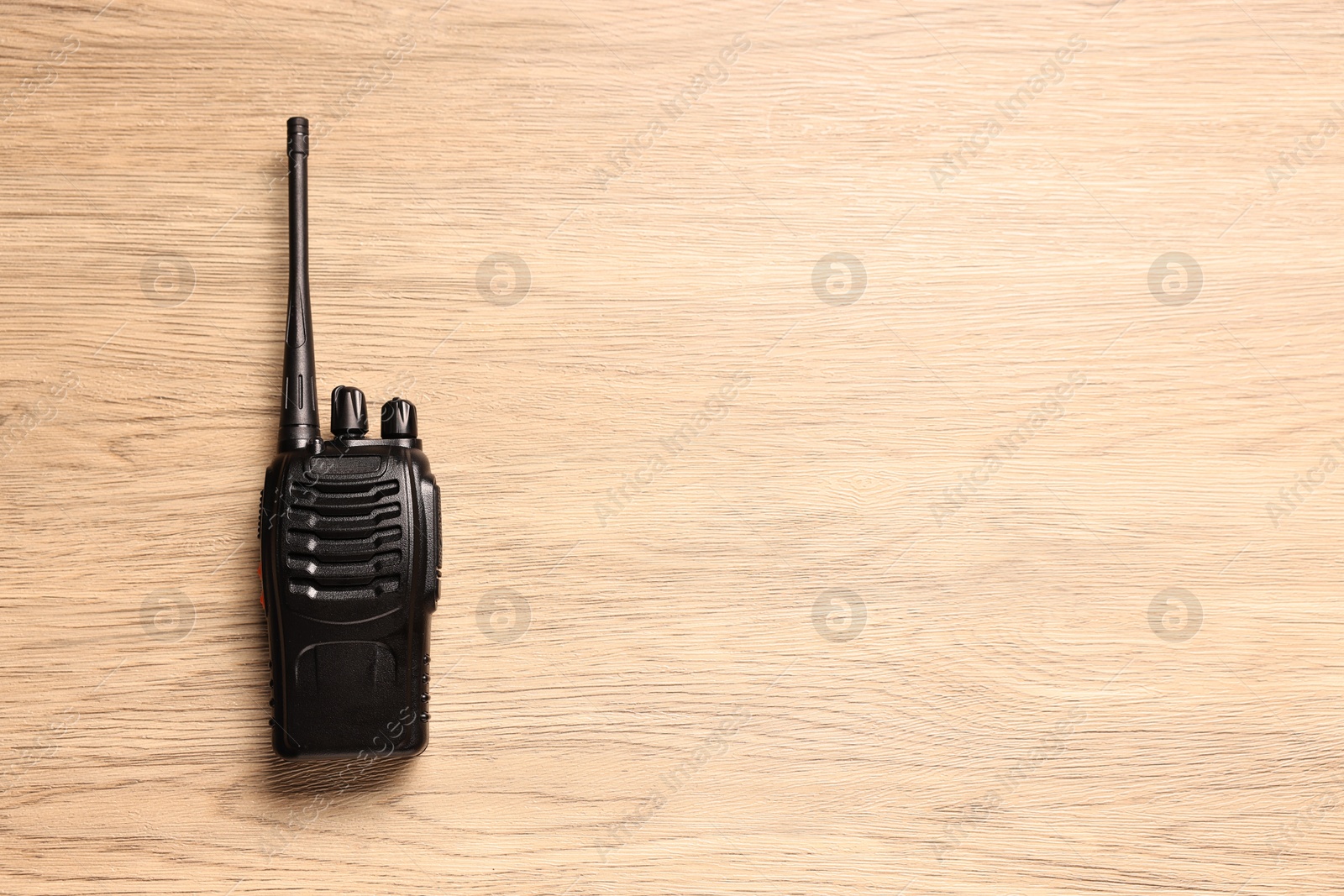 Photo of One walkie talkie on wooden table, top view. Space for text