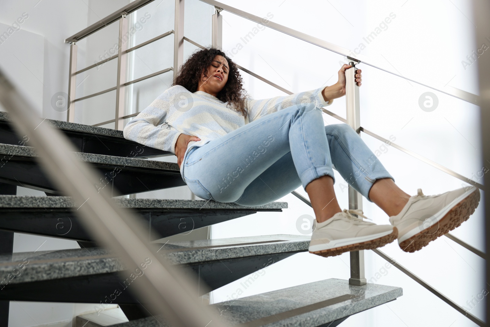 Photo of Injured woman on stairs in building after fall. Dangerous accident