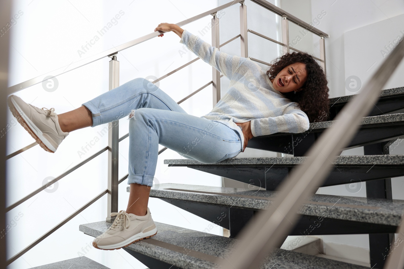 Photo of Injured woman on stairs in building after fall. Dangerous accident