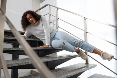 Photo of Injured woman on stairs in building after fall. Dangerous accident