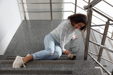 Photo of Injured woman on stairs in building after fall. Dangerous accident