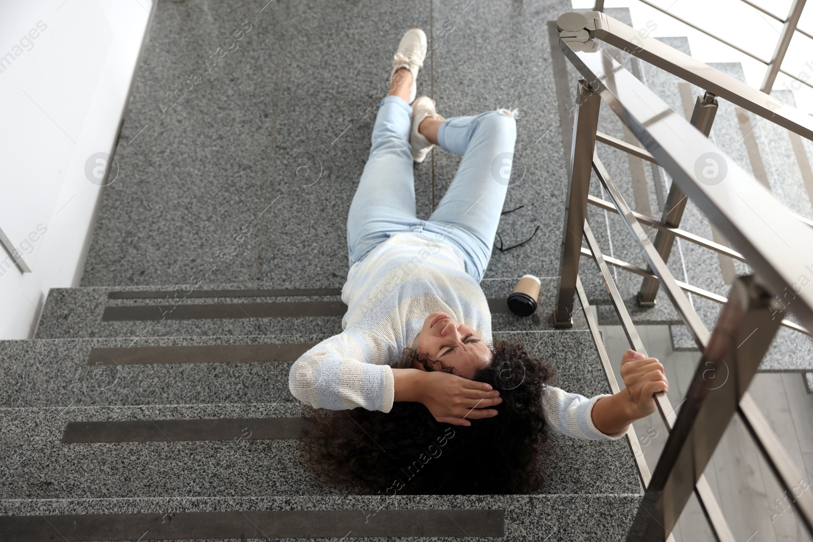 Photo of Woman with injured head on stairs in building after fall, above view. Dangerous accident