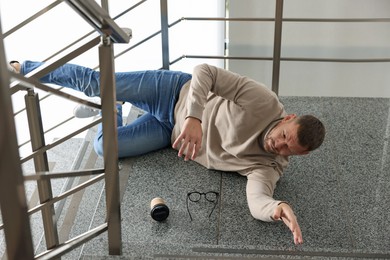 Photo of Injured man on stairs in building after fall. Dangerous accident