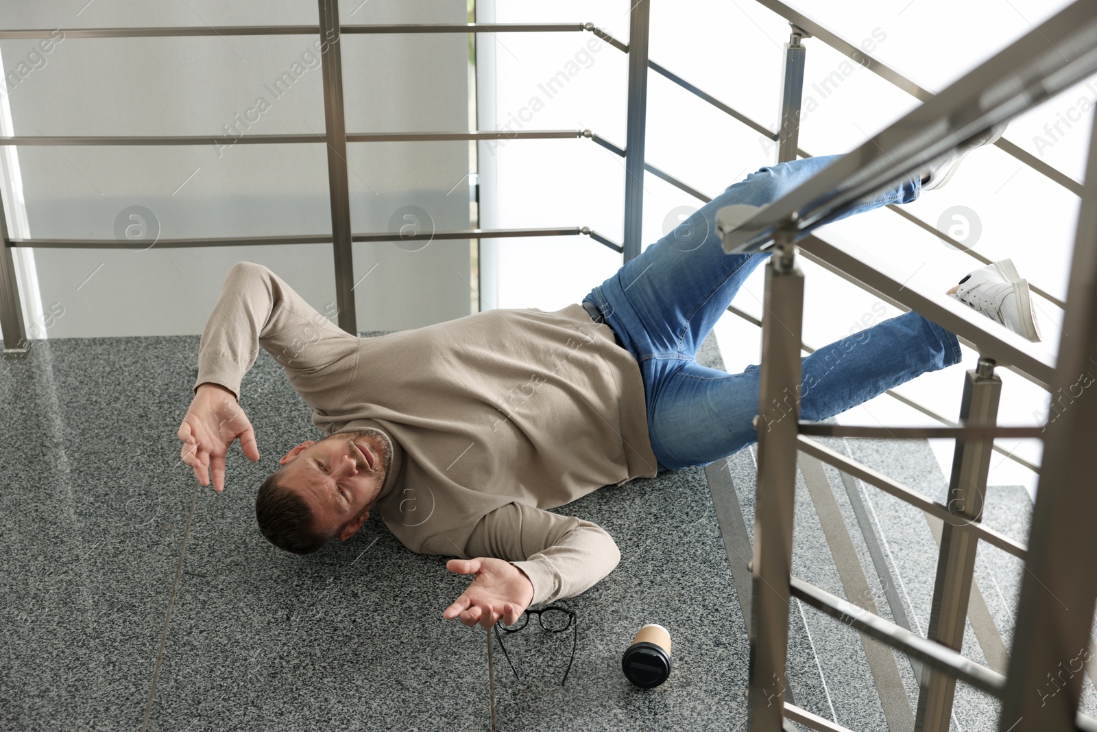 Photo of Injured man on stairs in building after fall. Dangerous accident