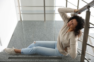 Photo of Injured woman on stairs in building after fall. Dangerous accident