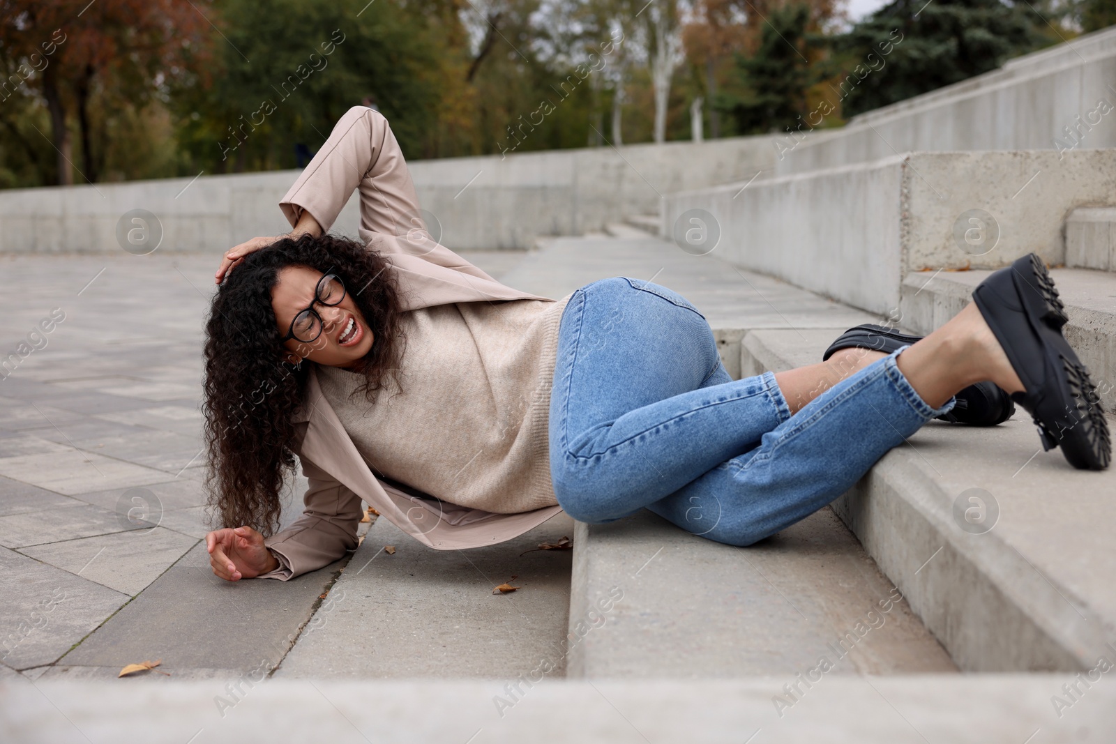 Photo of Injured woman on stairs outdoors after fall. Dangerous accident