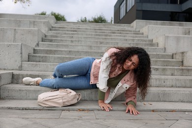 Photo of Injured woman on stairs outdoors after fall. Dangerous accident