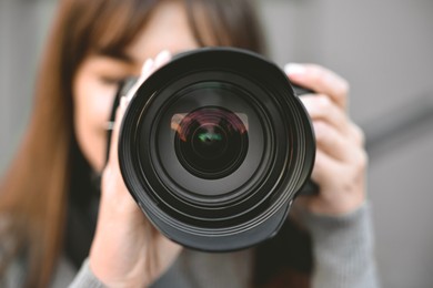 Photo of Professional photographer taking picture with camera outdoors, selective focus