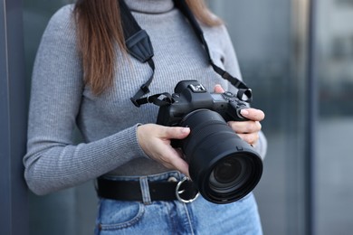 Photo of Professional photographer with digital camera outdoors, closeup