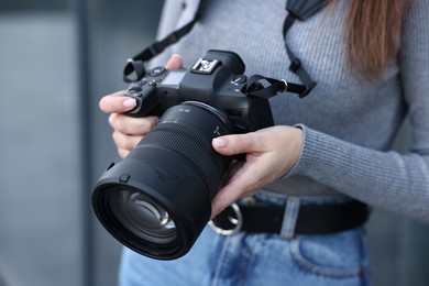 Photo of Professional photographer with digital camera outdoors, closeup